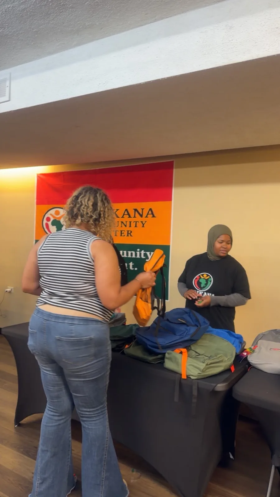 A volunteer helping a family select backpacks and school supplies.