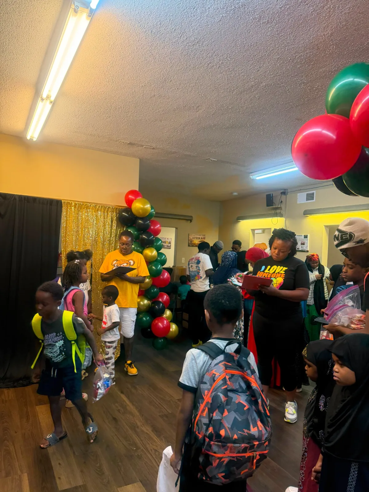 Children receiving backpacks as volunteers support event check-in.